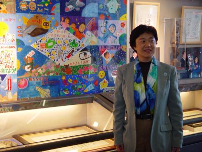 「向井千秋飛行士応援旗」の前に立つ向井氏の画像
