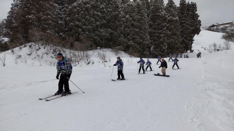 スキー教室でゲレンデを滑り降りる生徒