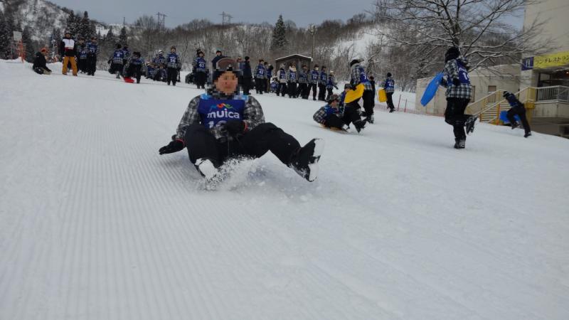 スキー教室でクラス対抗そり滑りを行う生徒