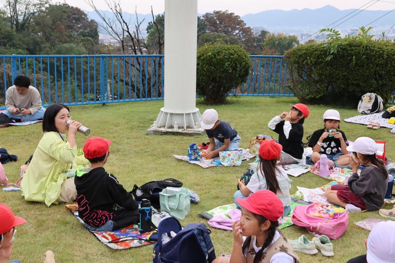 遊園地でお弁当を食べる児童