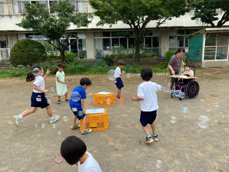 校庭でしゃぼん玉をする児童