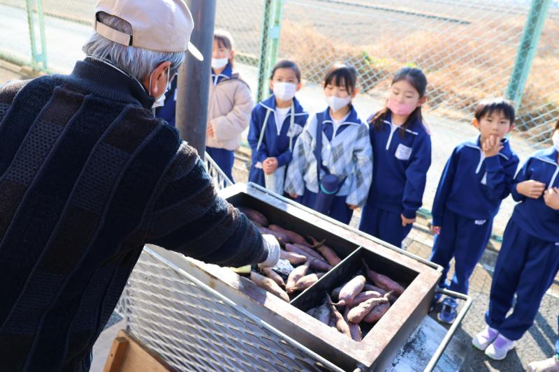 地域の人から焼き芋作りを教えてもらう児童達