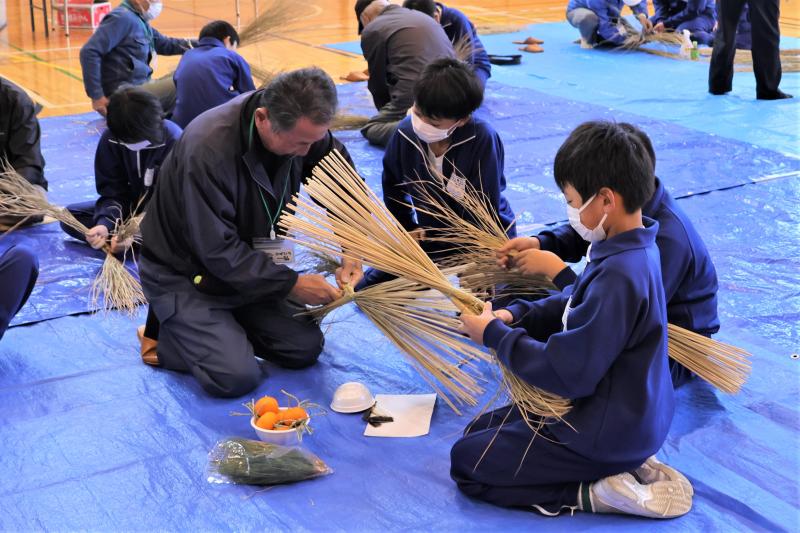 地域の方にしめ縄作りを教えてもらう児童達